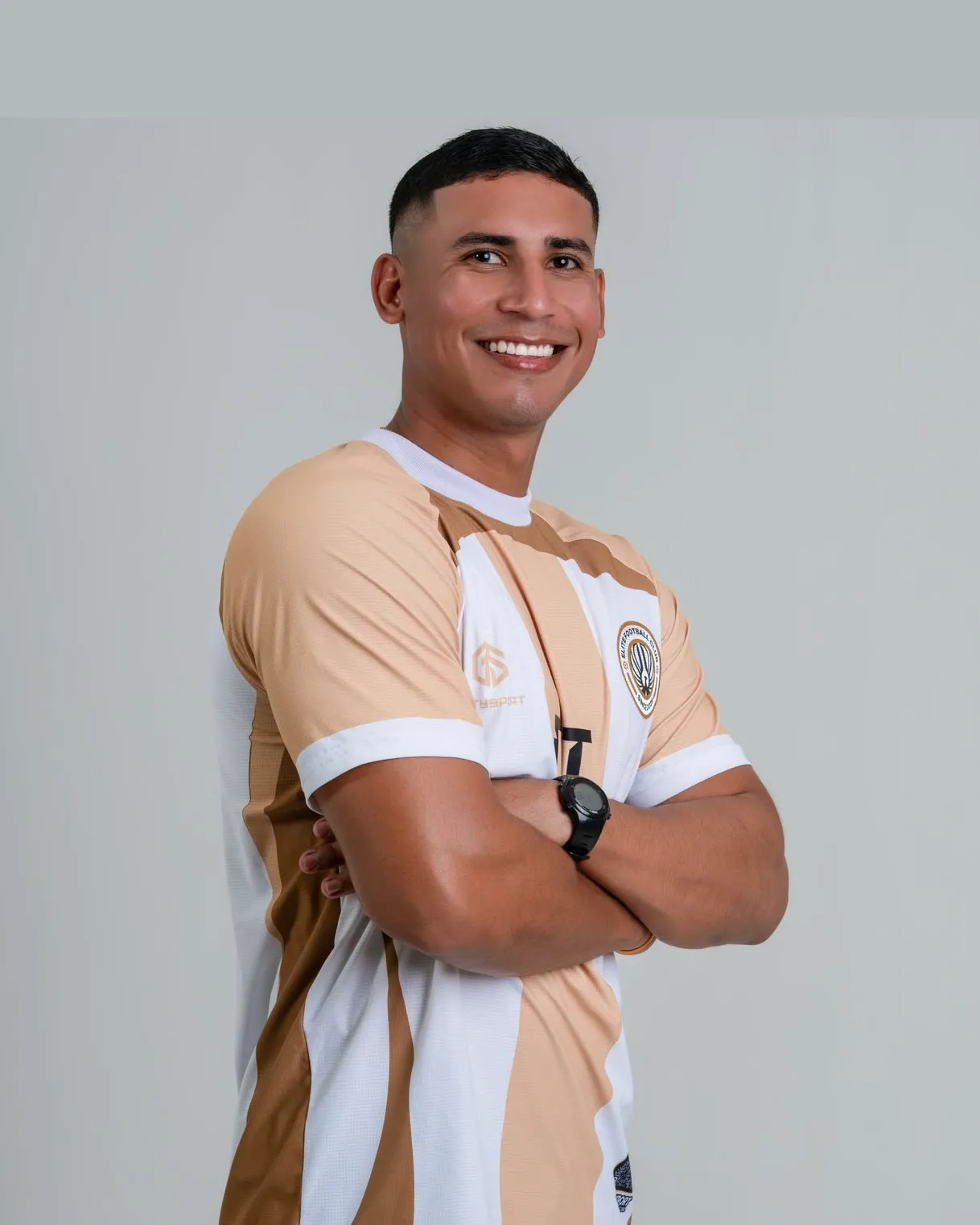 Andrés Rubiano sonriendo, de brazos cruzados y con la indumentaria del club, en fondo de estudio