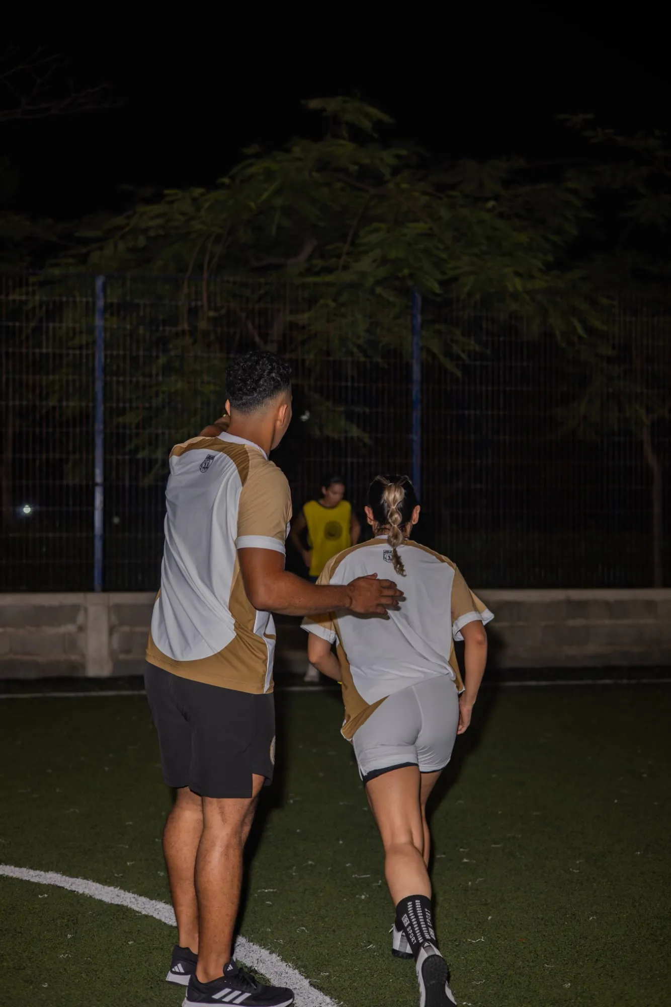 El entrenador acompañando a una jugadora con la mano en la espalda durante un ejercicio de carrera