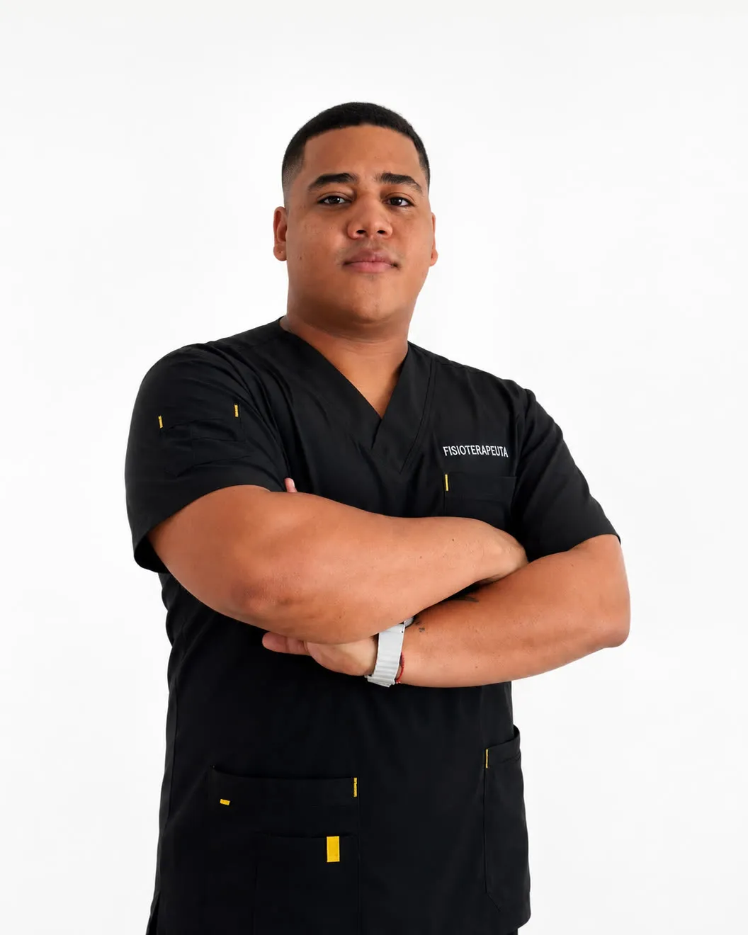 Juan Sebastián Torres de brazos cruzados, con uniforme negro de fisioterapeuta, en fondo blanco