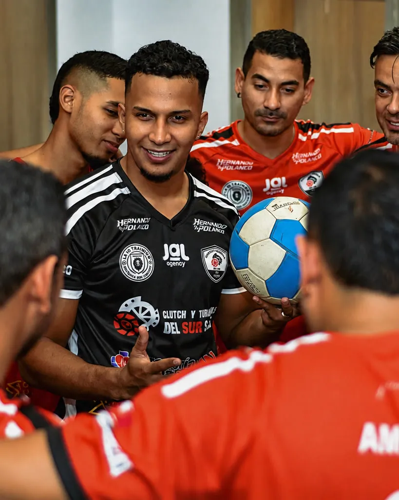 El entrenador con el balón en la mano hablando al equipo reunido en el camerino