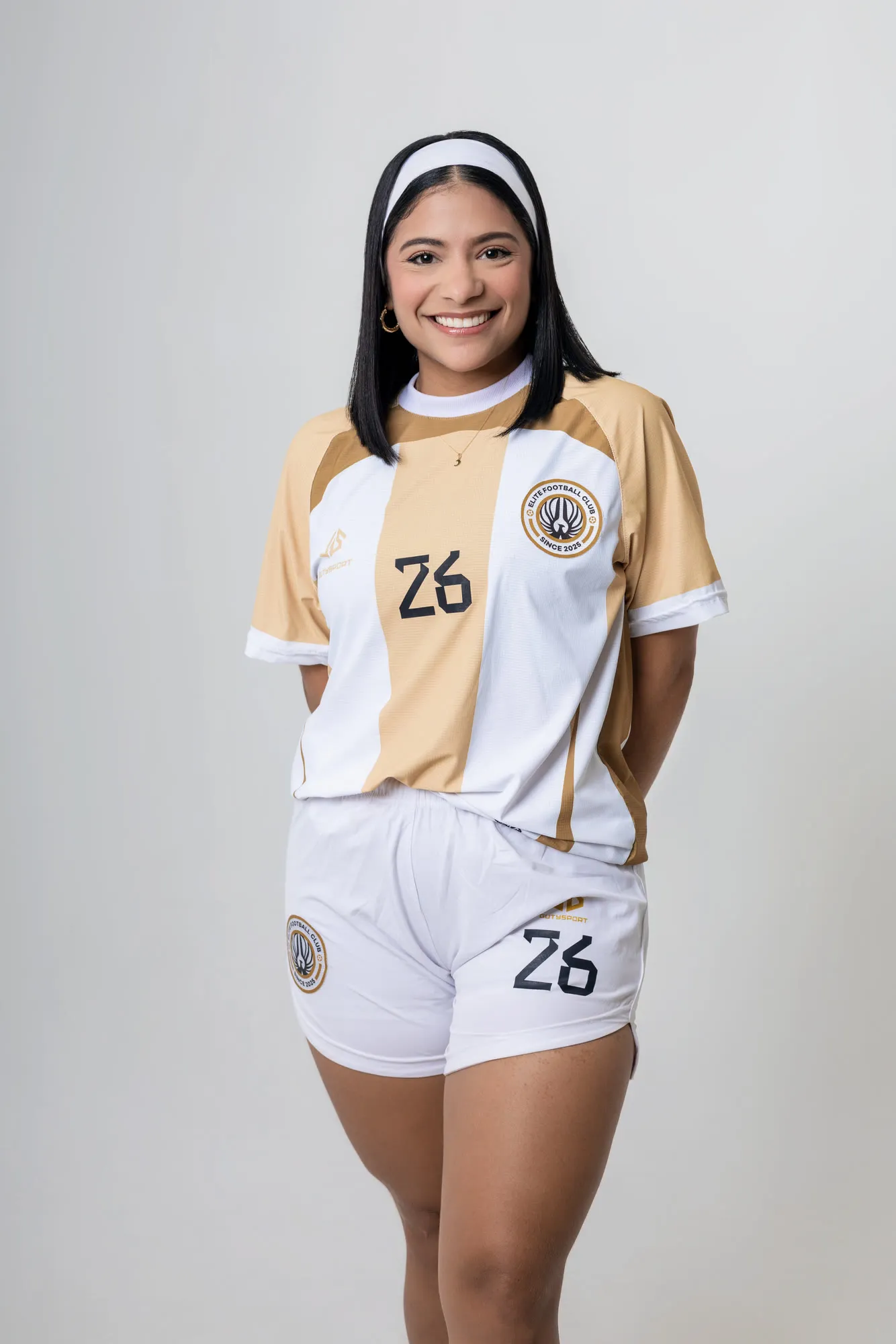 Jugadora número 26 sonriendo en estudio, con la indumentaria blanca y dorada