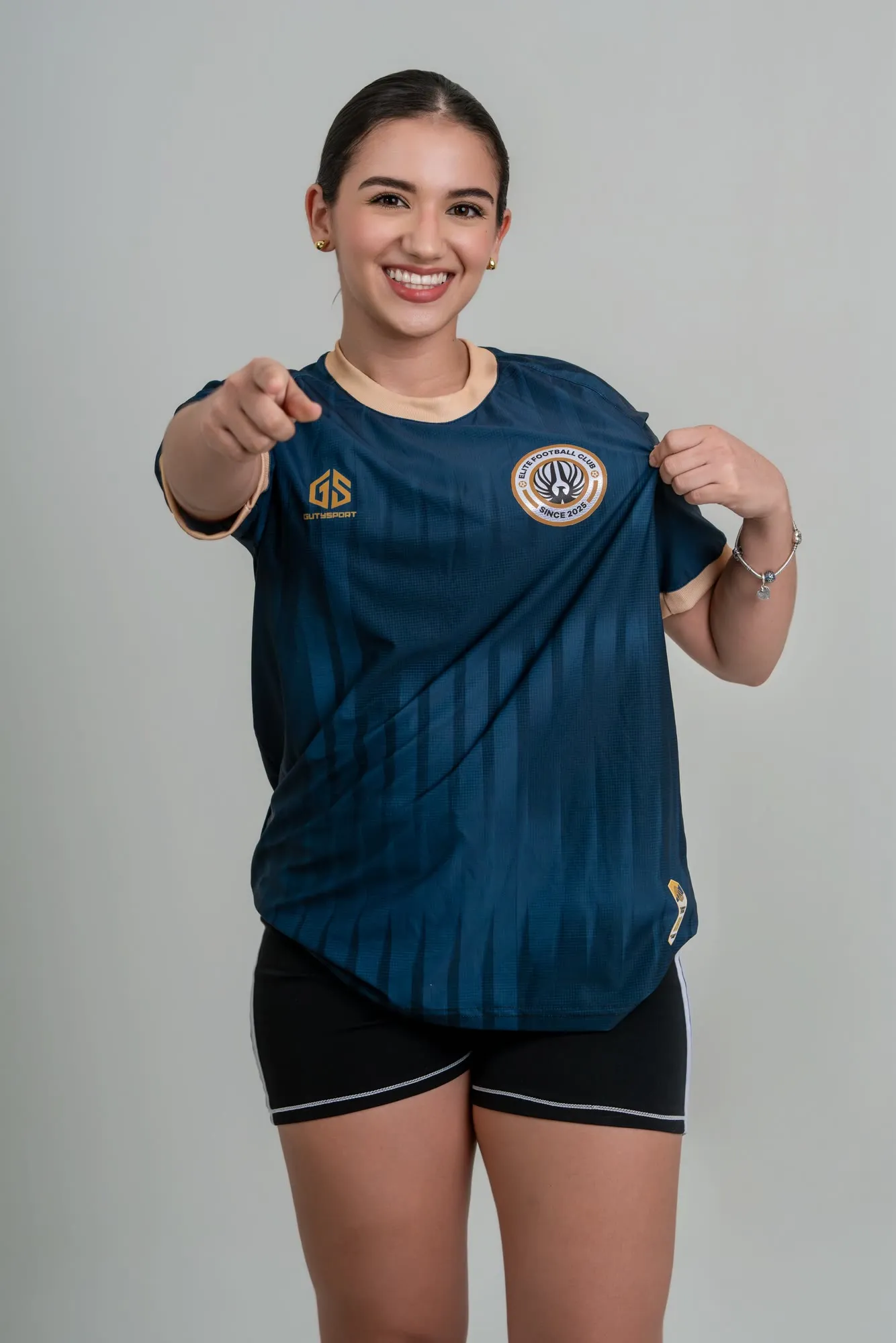 Jugadora en estudio señalando a cámara con la camiseta azul del club